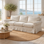 White sofa in a bright living room with large windows and a view of water.